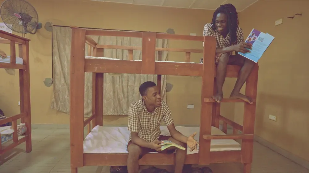 Two boarders in the dormitory, one reading on the top bunk