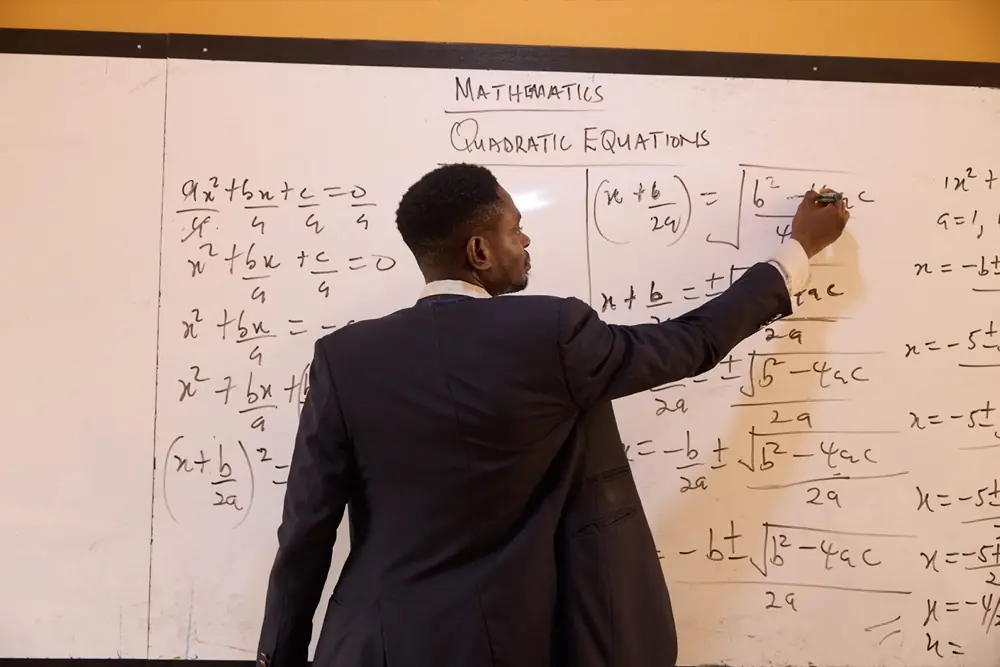 A teacher working through a problem at the whiteboard